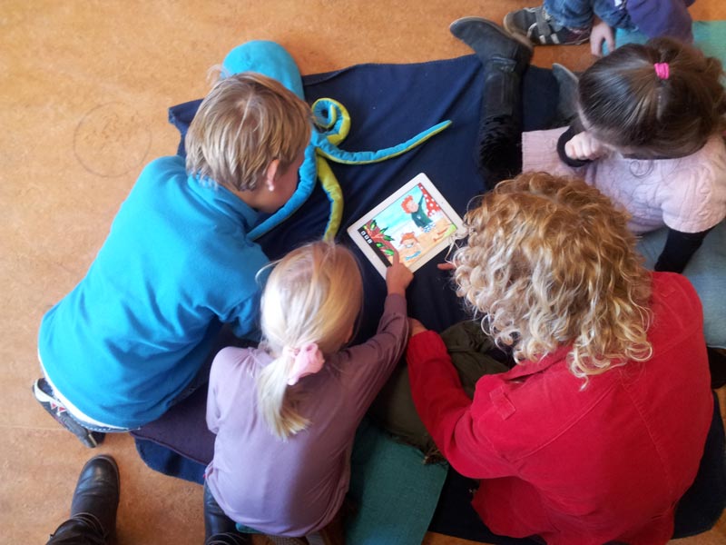 Charlotte en kinderen kijken samen naar de Ipad
